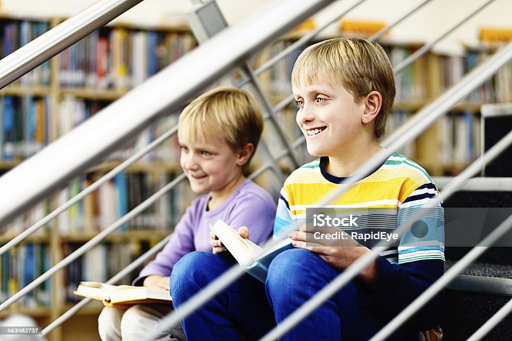 Sorrindo irmãos Sente-se na biblioteca com livros de Passos - Foto de stock de 10-11 Anos royalty-free