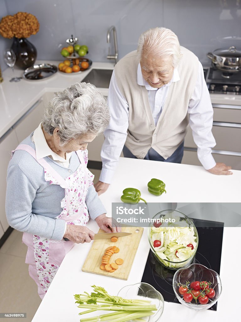 senior couple chatting in kitchen high angle view of a senior couple talking while preparing meal. Senior Adult Stock Photo