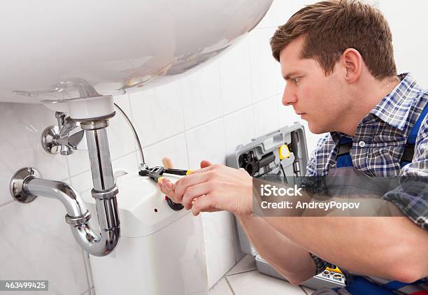 Young Plumber Fixing A Sink In Bathroom Stock Photo - Download Image Now - Plumber, Repairing, Sink
