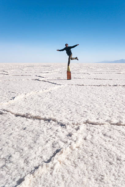 istock Man balancing on a bottle in salt flats 463509529