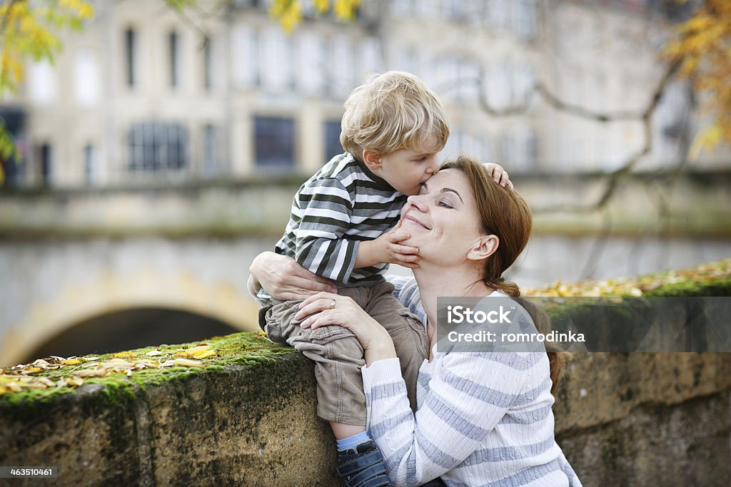 Adorable little son and mother in autumn city. Adorable little boy and mother hugging in autumn city Embracing Stock Photo