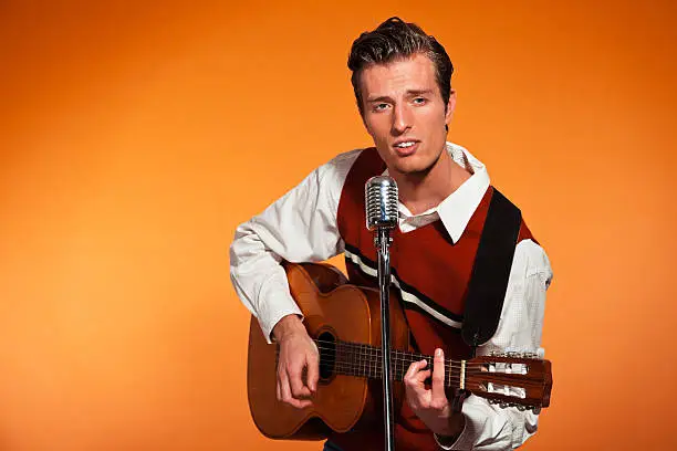 Photo of Retro fifties rock and roll singer playing accoustic guitar.