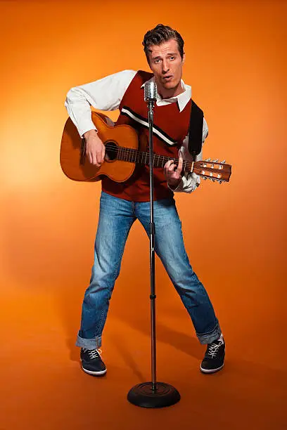 Photo of Retro fifties rock and roll singer playing accoustic guitar.