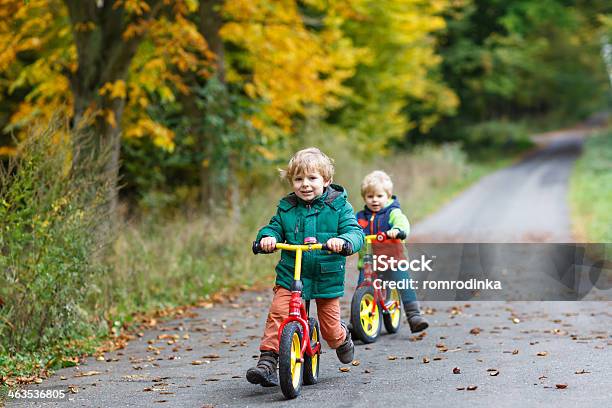 Two Little Siblings Having Fun On Bikes In Autumn Forest Stock Photo - Download Image Now