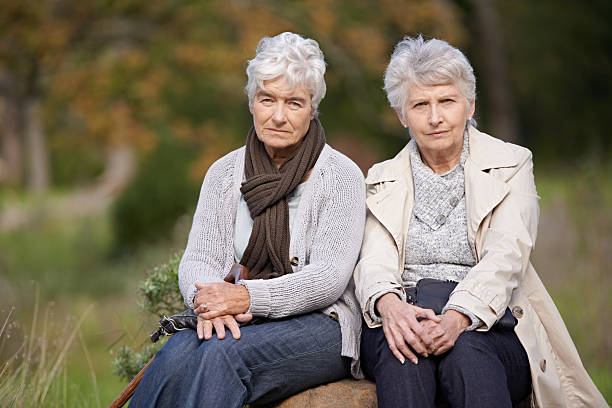We're too old for this... Two senior woman sitting outside on a boulder looking at the camera ugly old women stock pictures, royalty-free photos & images
