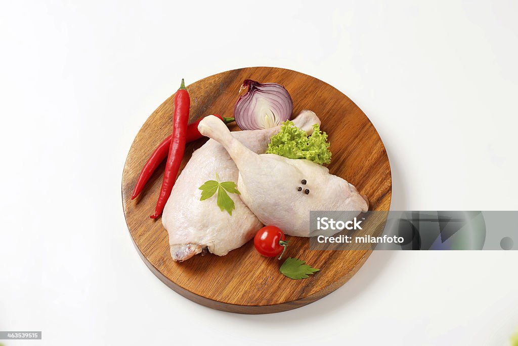 raw duck legs with vegetables two raw duck legs with vegetable garnish on round wooden cutting board Animal Body Part Stock Photo