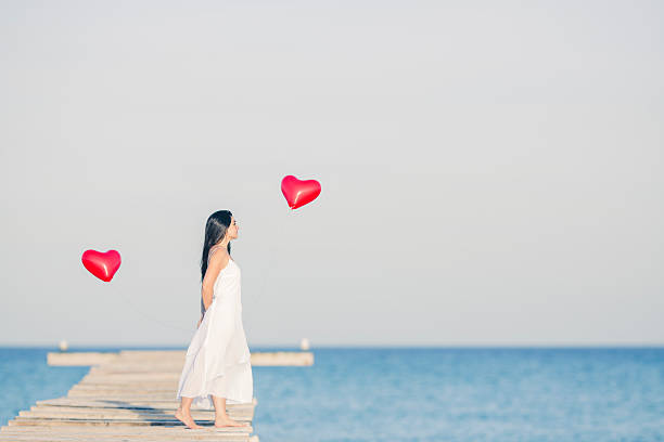 istock woman on the beach with two heart balloons 463539593