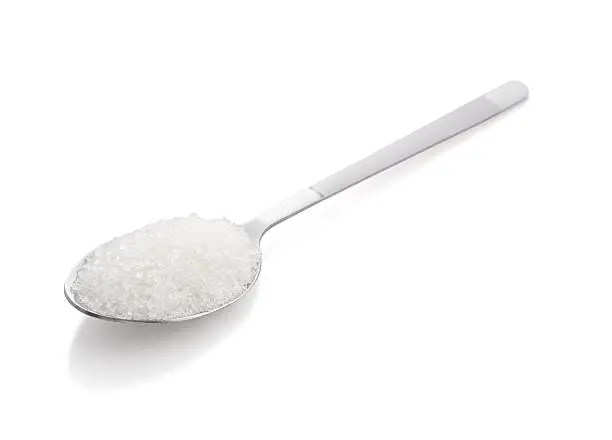 Salt or sugar on a teaspoon on white background, isolated