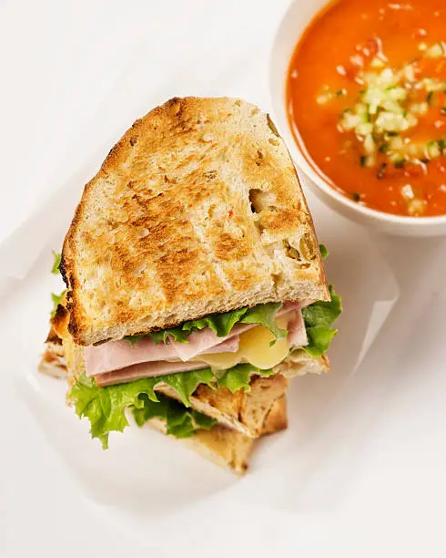 Tomato soup and grilled cheese sandwich on white background