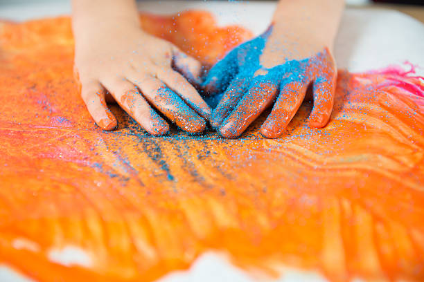 messy paint Child finger paints with glitter sand on his handshttp://2.bp.blogspot.com/-6uFsvUizzNg/T_85WkEZpeI/AAAAAAAABDs/ePjRC0VoP5M/s1600/kids.jpg sensory perception photos stock pictures, royalty-free photos & images