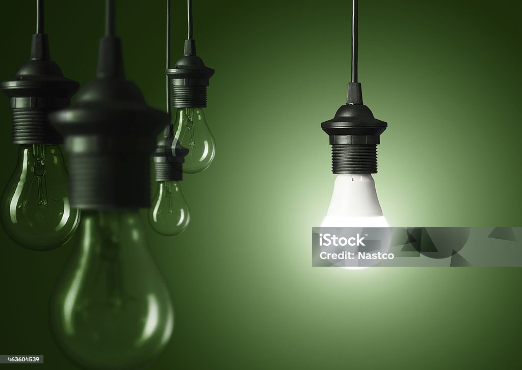 Standing out of the crowd Standing out of the crowd or great idea concept, glowing light bulb over green background Light Bulb Stock Photo