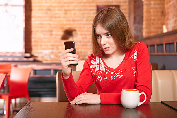 belle fille soulever sms sur téléphone mobile au café. - red text messaging cafe teenage girls photos et images de collection