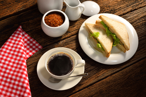 Coffee cup and sandwich on wood background.