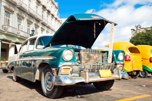 Broken retro-car with open hood parked on one of streets of Havana, Cuba
