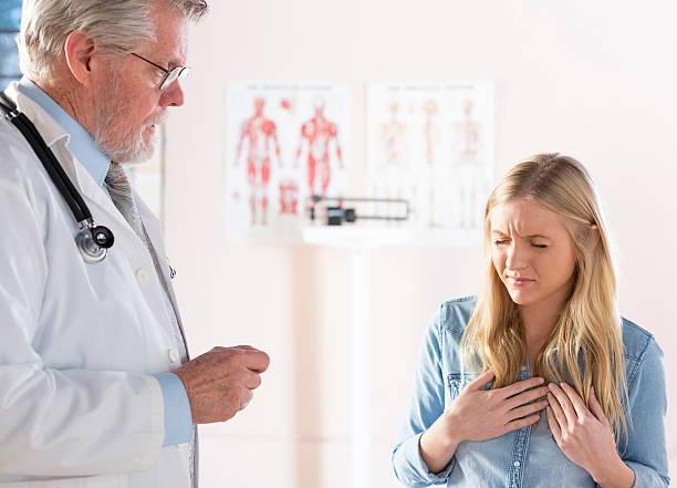 A distressed women describing her symptoms to a doctor A young female patient describes her symptoms to her doctor. gastroesophageal reflux disease photos stock pictures, royalty-free photos & images