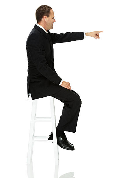 istock Happy businessman sitting on stool and pointing 463638825