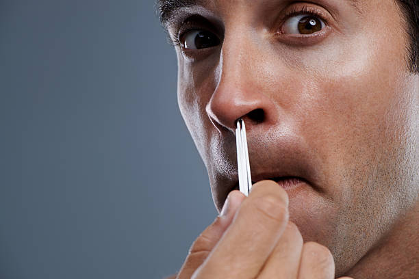 Taking care of the smaller details Closeup studio shot of a young man plucking his nosehair human nose stock pictures, royalty-free photos & images