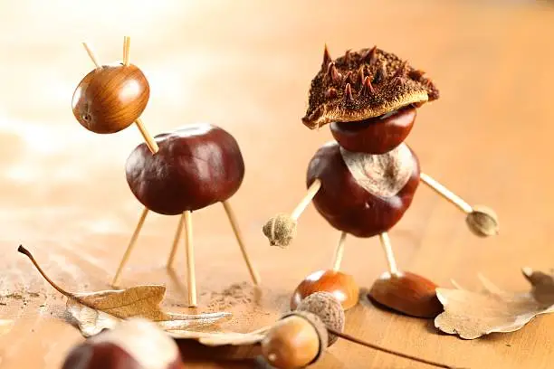 Chestnut and acorn figurines on wooden table. Selective focus, shallow DOF.