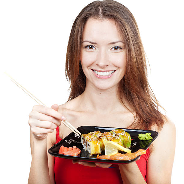 istock beautiful brunette woman eating sushi 463671323