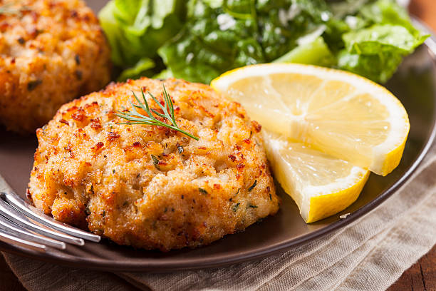 Plate of homemade organic crab cakes with veg and lemon Organic Homemade Crab Cakes with Lemon and Tartar Sauce bumpy stock pictures, royalty-free photos & images