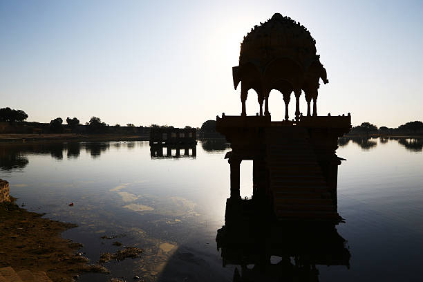 Hindu temple on lake in early morning, Jaisalmer A hindu temple in baklight on the small lake of Jaisalmer in early morning, India. jaisalmer stock pictures, royalty-free photos & images