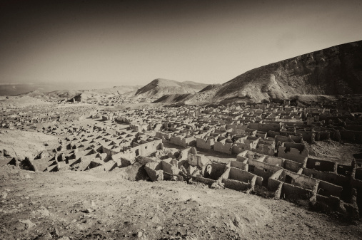 Panorama over an abandoned ghost town in desert mountains in antique sepia style