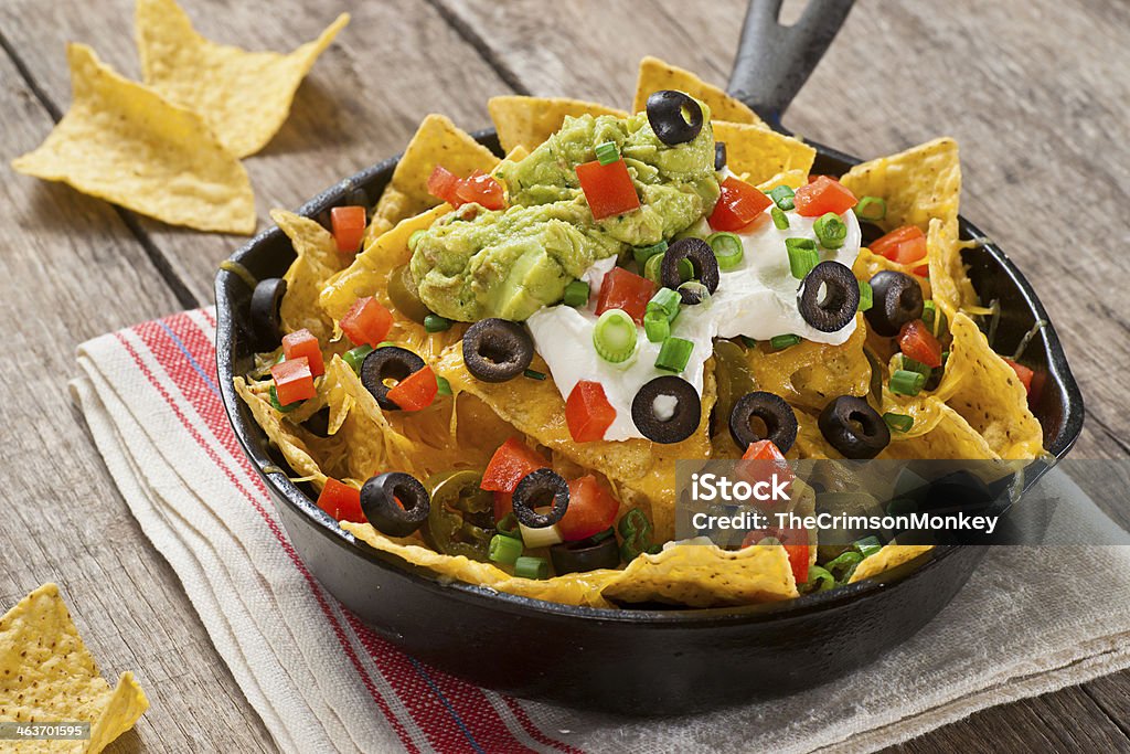 Nachos Nachos with cheddar cheese, green onions, jalapenos, tomatoes, black olives, guacamole, and sour cream. Nacho Chip Stock Photo