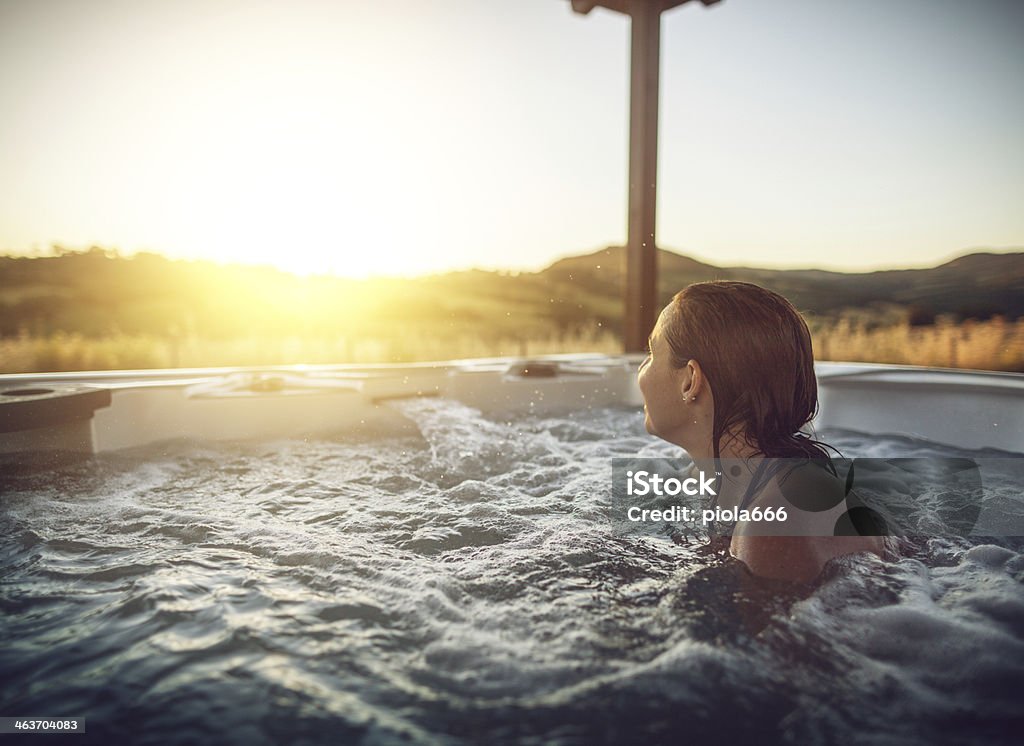 Woman in whirlpool hot tub Woman in whirlpool hot tub at sunset Hot Tub Stock Photo
