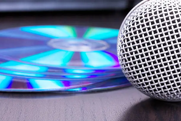 Photo of Microphone and cd disks on black table