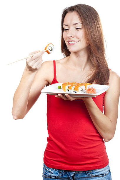 istock beautiful brunette woman eating sushi 463722979