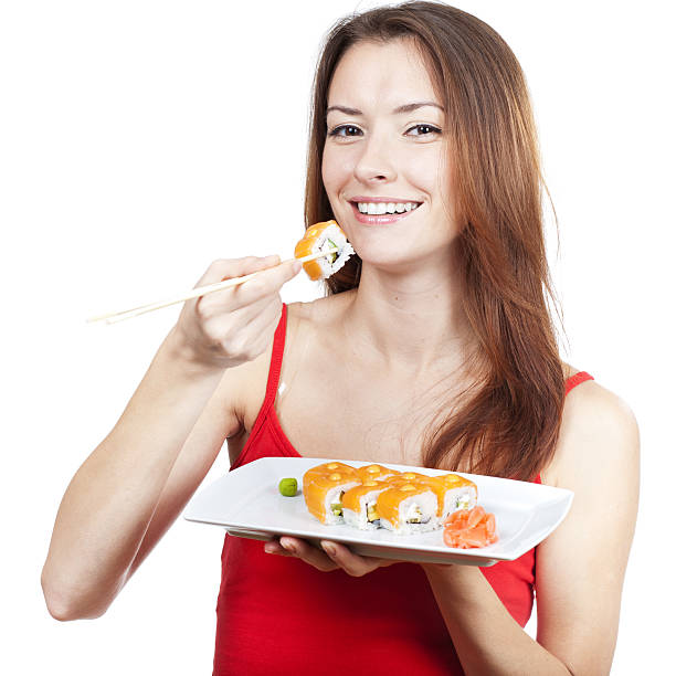 istock beautiful brunette woman eating sushi 463722981