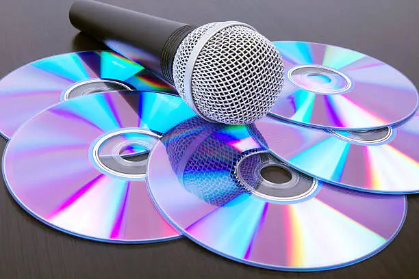 Photo of Microphone and dvd disks on black table