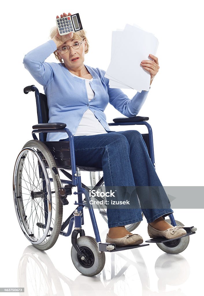 Financial problem Portrait of worried senior woman sitting in wheelchair and looking through bills. Studio shot on white background. 60-69 Years Stock Photo