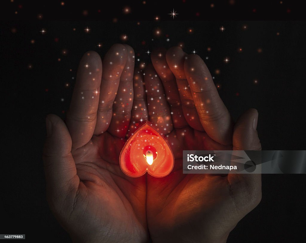 burning heart on hands. burning heart shaped candles on hands. Candle Stock Photo