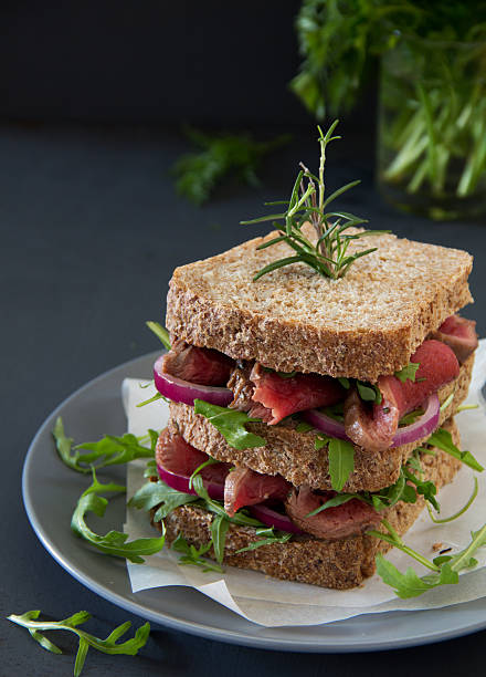 istock Grain bread sandwich with roast beef, onion and arugula. 463779921