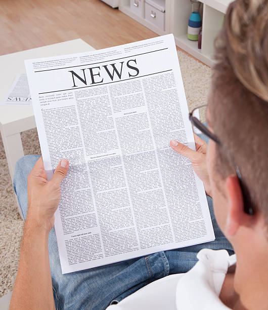 istock Young man reading newspapers and relaxing on couch 463781651