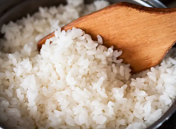 White rice in a metal pan, cooked cereals. Selective focus with shallow depth of field.