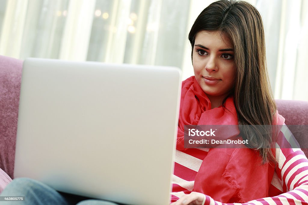 Young beautiful woman and using laptop Young beautiful woman sitting on the sofa and using laptop at home Adult Stock Photo