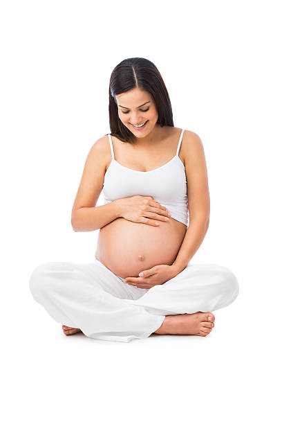Happy pregnant woman holding her belly A happy pregnant woman holding and looking at her belly. Isolated on a white background. 8 months pregnant stock pictures, royalty-free photos & images