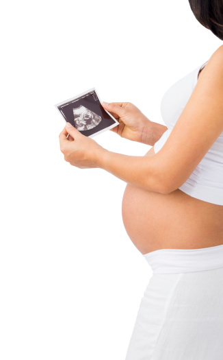 Close up of a pregnant woman looking at a print of her baby's ultrasound. Isolated on a white background.