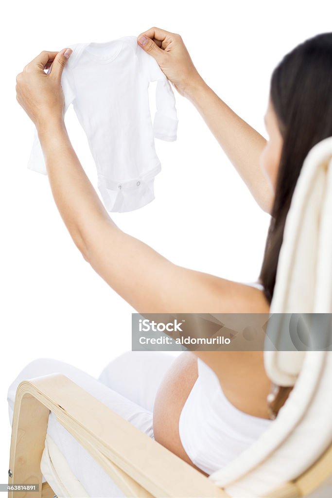 Pregnant woman holding up baby clothes A pregnant woman holding up baby clothes. Isolated on a white background. 30-34 Years Stock Photo