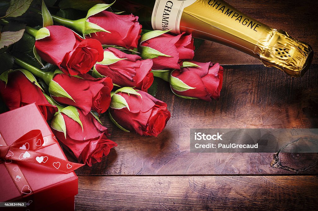 Valentine's setting with red roses, champagne and gift Valentine's setting with red roses, champagne and gift on old wood background Champagne Stock Photo
