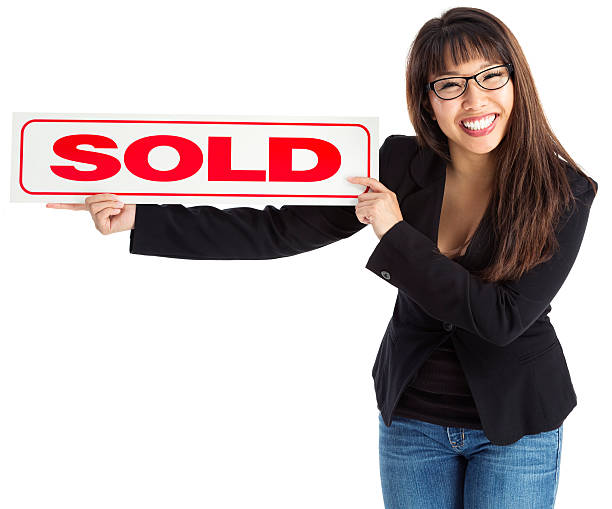 A bright large for SOLD sign stands on the side of the street. This is a close shot of the word SOLD.