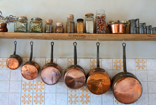 Old saucepans hanging from in a traditional-style kitchen