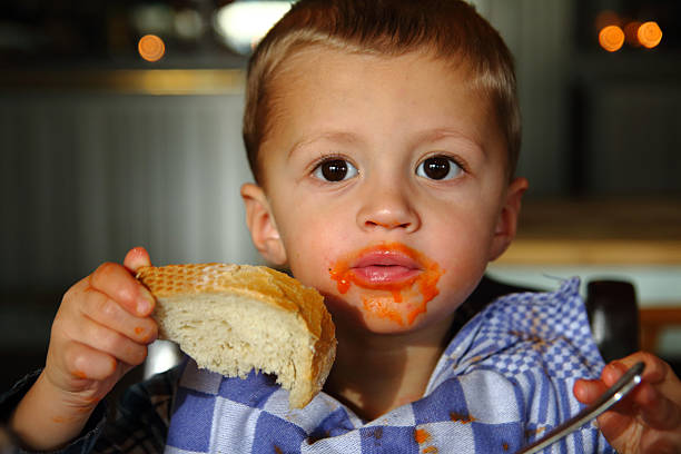 Little boy eating soup and messing his face up