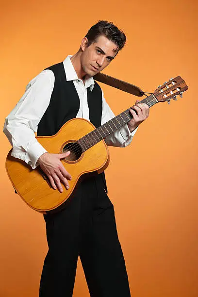 Photo of Retro country male guitar player wearing black suit. Studio shot.