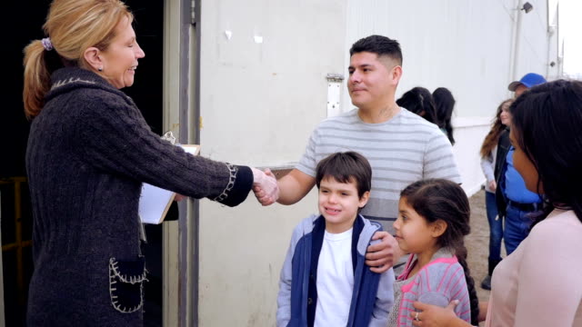 Food bank volunteer greeting Hispanic family while in line for donations