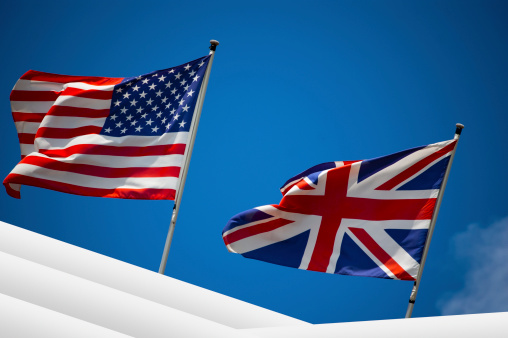 English and American flag in the wind on blue sky - U.S. and UK