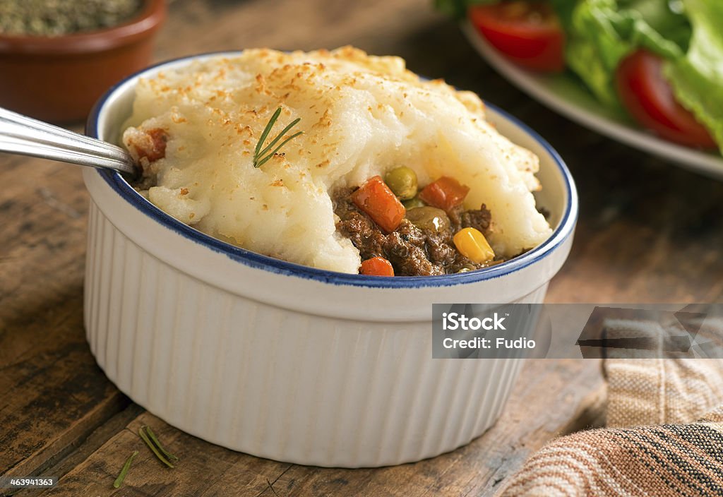 Bowl of shepherds pie on the dinner table A piping hot shepherd's pie in a ramekin on a rustic tabletop setting. Savory Pie Stock Photo
