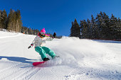 Action shot of a snowboarding girl, zooming downhill